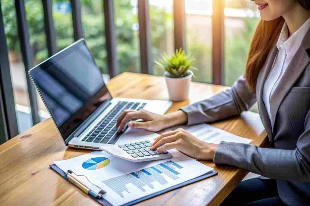 An accountant working through a client's reports with a calculator and laptop